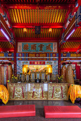 Vibrant interior of Teng Yun Temple, Bandar Seri Begawan, Brunei Darussalam. Features an ornate altar with statues, rich red and gold decor, and traditional Chinese architectural details.