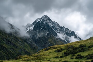 Fototapeta premium Mountain Peak Surrounded By Clouds Under Overcast Skies With Green Vegetation in Foreground