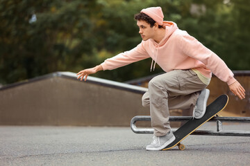 Handsome young man riding skateboard at skate park