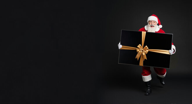 Santa claus man in red suit delivering large black gift box with gold ribbon on dark background. Holiday present surprise and new year celebration concept. Festive delivery tradition and winter joy - Powered by Adobe