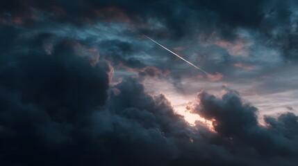 Obraz premium Dramatic twilight sky with dark clouds soft sunset colors and a distinct airplane contrail