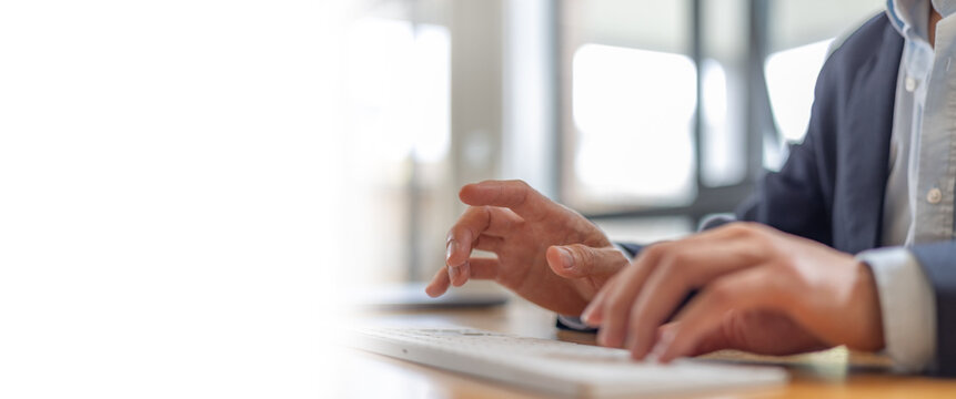 Close-up of businessman hands typing on wireless keyboard in modern office, representing productivity, remote work, and digital business communication.