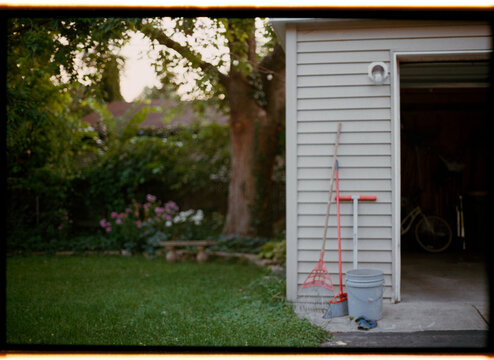 Garden Tools Beside Garage in Evening Light With Flowers