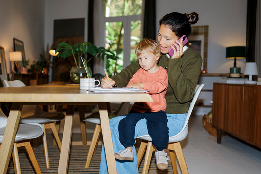 Mother multitasking working from home with son