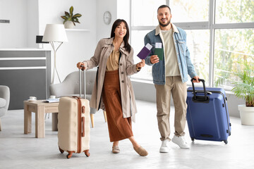 Young couple with passports and suitcases waiting for their flight in airport lounge