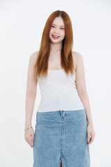 Obraz premium Studio portrait of asian attractive beautiful young woman in white tank top, denim skirt, posing smile on white background, minimal fashion style casual outfit lifestyle clothing advertising concept.