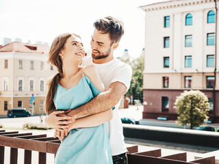 Obraz premium Portrait of smiling beautiful woman and her handsome boyfriend. Woman in casual summer jeans dress. Happy cheerful family. Female having fun. Couple posing on the street background