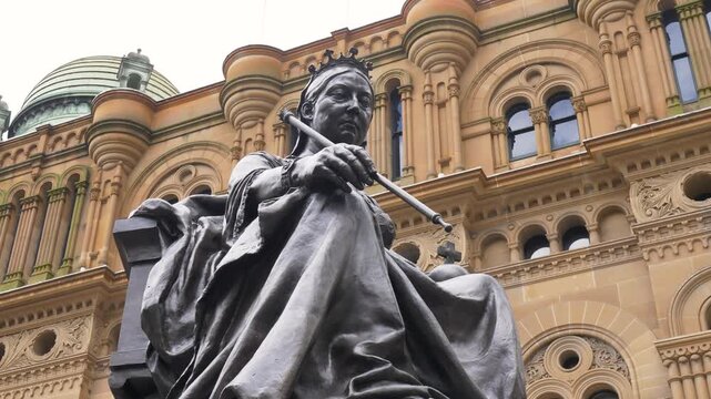 Slow motion close up of Queen Victoria on her throne public sculpture and bronze statue monument with historic building in the background in Town Hall Sydney City NSW Australia history culture tourism