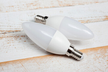 Two LED lamps with E14 sockets lying on a wooden surface.
