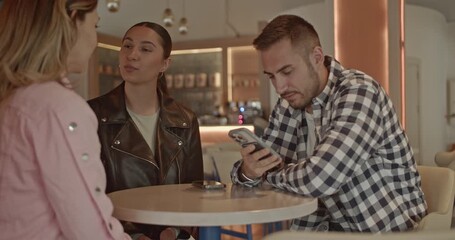 Young professionals engage in a collaborative discussion, utilizing mobile technology within a contemporary cafe. They are sharing ideas and planning, highlighting work dynamics and digital connection - Powered by Adobe