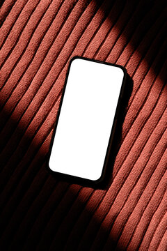 Smartphone With White Screen on Textured Fabric Under Bright Light