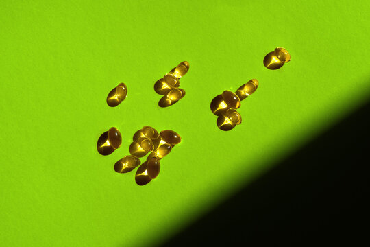 Golden Omega 3 Capsules on Vivid Green Backdrop with Copy Space.