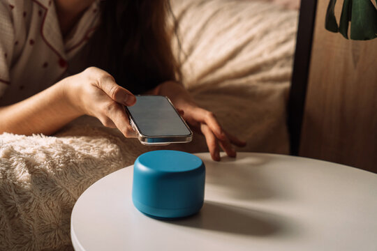Pairing smartphone close to blue AI smart home speaker. High quality photo