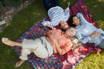 three &nbsp;mid-life woman friends relaxing lying in the garden on a blanket on a summer day. family gatherings. Mid-Life Women’s Healt