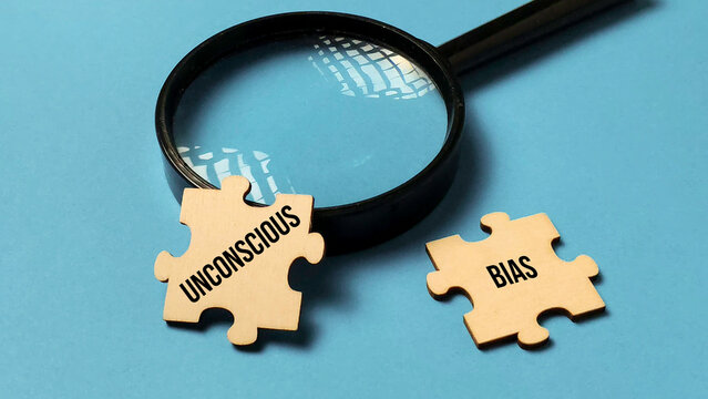 Examining Unconscious Bias: Magnifying Glass Focuses on Two Puzzle Pieces on a Blue Background