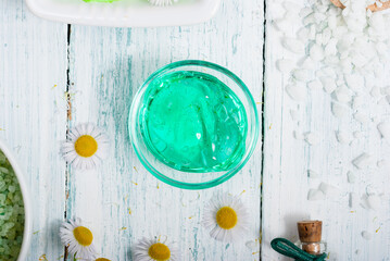 beauty product samples with chamomile flowers on white wooden table
