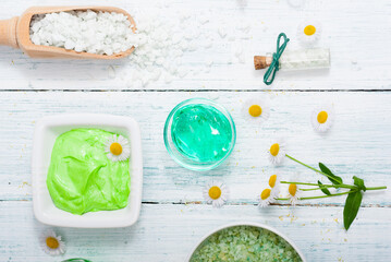 beauty product samples with chamomile flowers on white wooden table