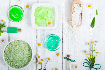 beauty product samples with chamomile flowers on white wooden table