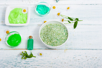 beauty product samples with chamomile flowers on white wooden table