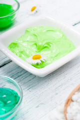 beauty product samples with chamomile flowers on white wooden table