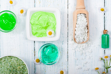 beauty product samples with chamomile flowers on white wooden table