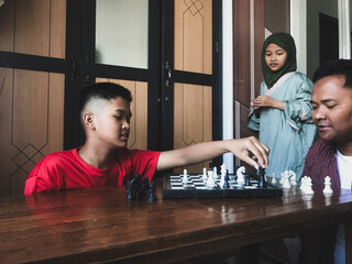 A father playing chess with his children