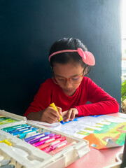 Little girl coloring with crayons at home