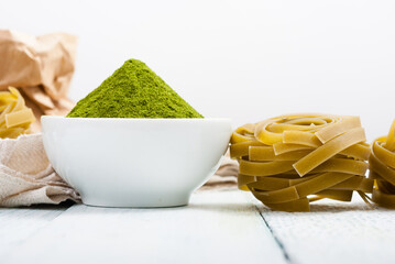 uncooked taglatelle pasta and ingredients: grounded spinach powder and whole wheat flour