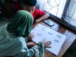 An older brother drawing with his younger sister beside him