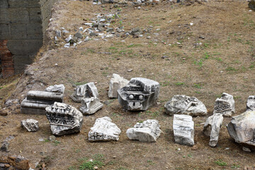 Ornate marble fragments from the Roman Forum lie scattered on the ground in Rome, Italy.