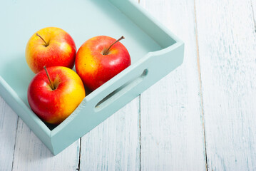 apples at blue tray, white wood table