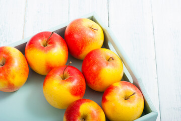 apples at blue tray, white wood table