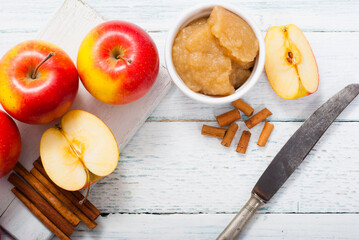 apple jam at porcelain dish, apples, cinnamon, white wood table background