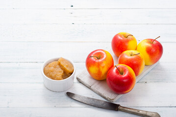 apple jam at porcelain dish, apples, cinnamon, white wood table background