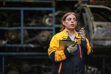 Female hispanic technician inspect used car damaged part at scrap yard warehouse recycle area....