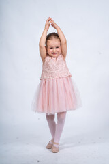 Rear view of a little girl in a pink tutu and ballet slippers, standing gracefully with a tiara on her head, holding pointe shoes.Little ballerina practicing dance moves.  © Alaphotography
