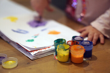 Child finger painting with bright colorful paints on paper during an art lesson or home activity. Early childhood creativity, fine motor skills, and the learning through play concept.