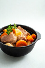 Hearty stew with meat and vegetables in a black bowl