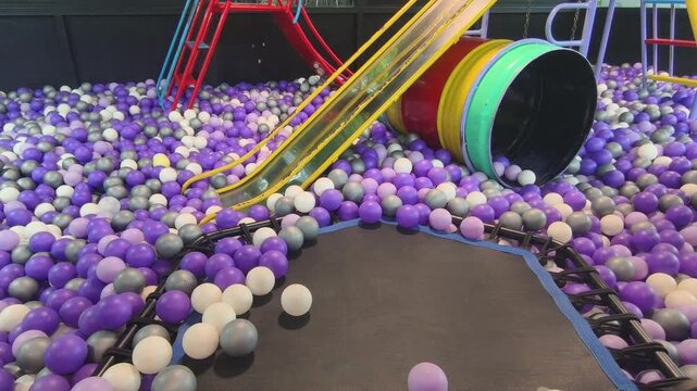 Vibrant play area with balls, slide, and tunnel offers fun activities for children to explore and enjoy in safe playground environment.