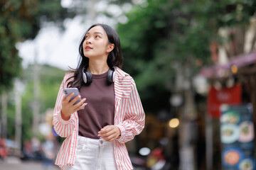 Young asian woman exploring city street looking up