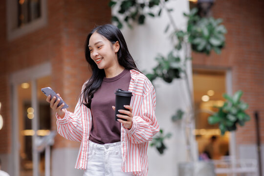 Young woman smiling using phone drinking coffee - Powered by Adobe