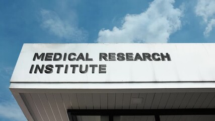 A medical research institute word sign displayed on a large facility under a clear blue sky, symbolizing scientific inquiry, discovery, disease study, and innovation