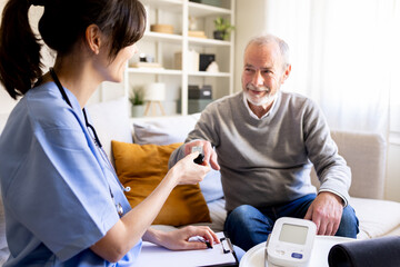 Nurse visiting elderly man at home taking blood sample for glycemia test