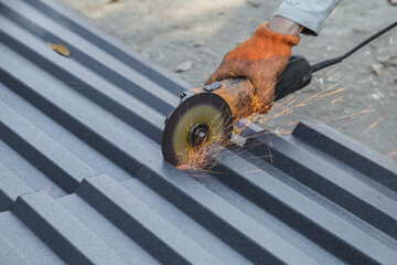 Man is cutting a metal roof with a circular saw. The sparks from the saw are flying everywhere, creating a dangerous and intense scene