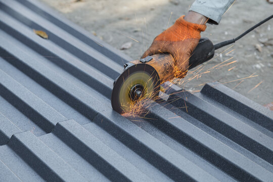 Man is cutting a metal roof with a circular saw. The sparks from the saw are flying everywhere, creating a dangerous and intense scene