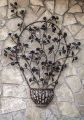 Metal flower basket with a metal flower arrangement hanging from a wall