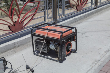 The generator stands on the sidewalk. The generator is used for welding.