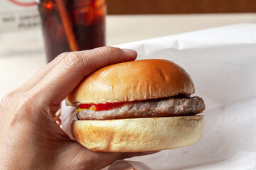 hand holding hamburgers over blurred restaurant background. 