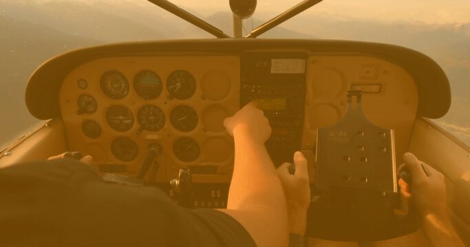 Fototapeta Pilot and co-pilot adjusting panel controls during sunset flight, with radio stack and yoke