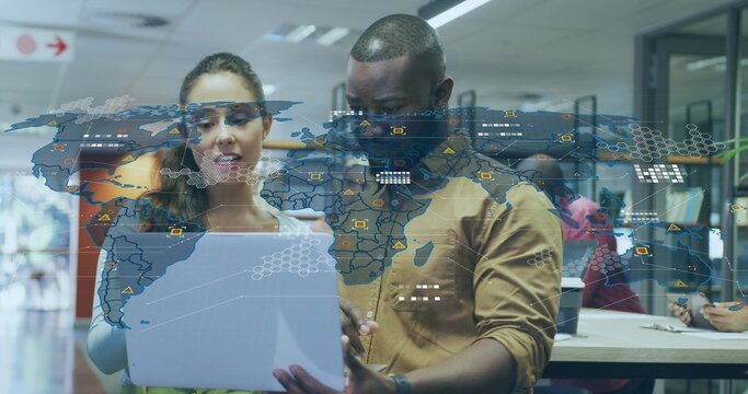 Reviewing tablet, woman in blouse and man in button-up shirt in open-plan office, with data overlay - Powered by Adobe